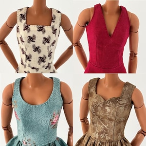 May include: Four doll dresses in various styles and colors. One dress is cream-colored with a dark paisley pattern, another is a deep red halter dress, a third is light blue with a floral print, and the last is brown with a floral pattern.