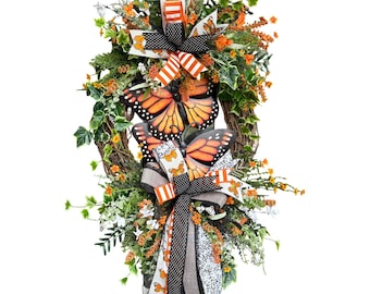 Corona de vid hecha a mano con mariposas monarca naranjas y negras para la puerta principal.