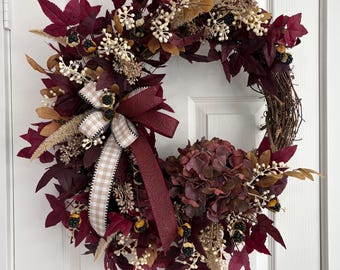 Elegante ghirlanda autunnale di vite color bordeaux e more per la porta d'ingresso.