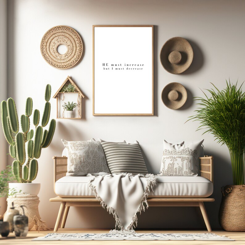 Puede incluir: Un sof&aacute; blanco con una manta blanca y almohadas en una sala de estar con una impresi&oacute;n enmarcada que dice "HE must increase but I must decrease". La habitaci&oacute;n est&aacute; decorada con decoraci&oacute;n de pared tejida y plantas en macetas.