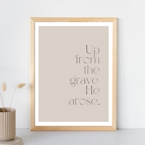 May include: A framed print with a beige background and black text that reads "Up from the grave He arose."