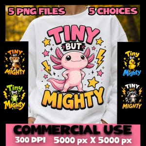 May include: A white sweatshirt featuring a central graphic of a pink axolotl with the text "TINY BUT MIGHTY" in pink and yellow. The design includes yellow stars and lightning bolts. Additional small animal graphics are shown on the sides.