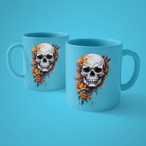Op de afbeelding: Twee lichtblauwe keramische mokken met een schedelontwerp. De schedel is wit met zwarte schaduw en is omgeven door oranje bloemen en donkere bladeren. De mokken hebben een gebogen handvat en een glad oppervlak.