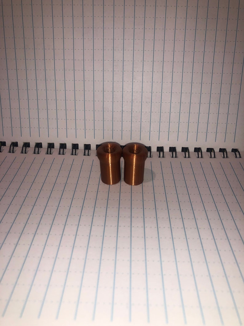 Peut inclure: Deux petits bouchons cylindriques de couleur cuivre.