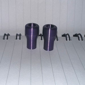 Peut inclure: Deux bouchons de bouteille en plastique violet. Les bouchons sont cylindriques avec un sommet l&eacute;g&egrave;rement &eacute;vas&eacute;.