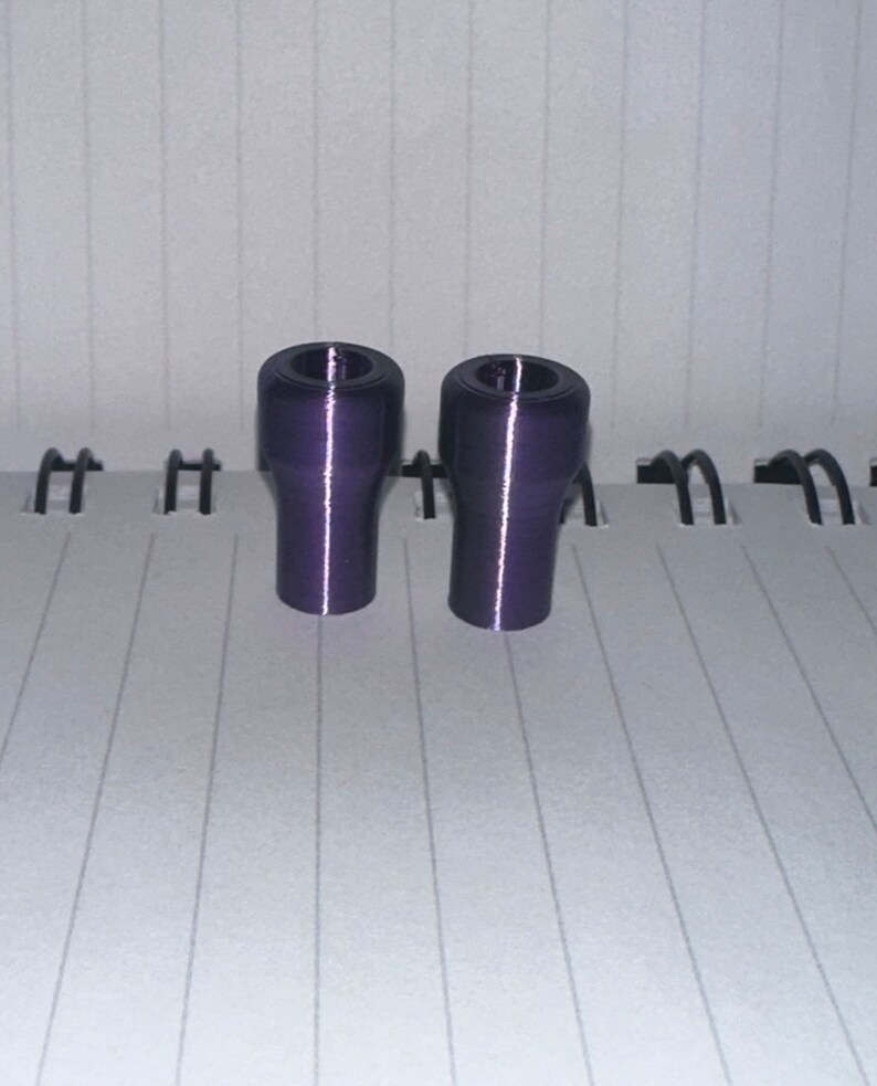 Peut inclure: Deux bouchons de bouteille en plastique violet. Les bouchons sont cylindriques avec un sommet l&eacute;g&egrave;rement &eacute;vas&eacute;.