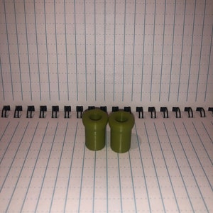 Peut inclure: Deux bouchons de bouteille en plastique vert olive avec un trou en haut.