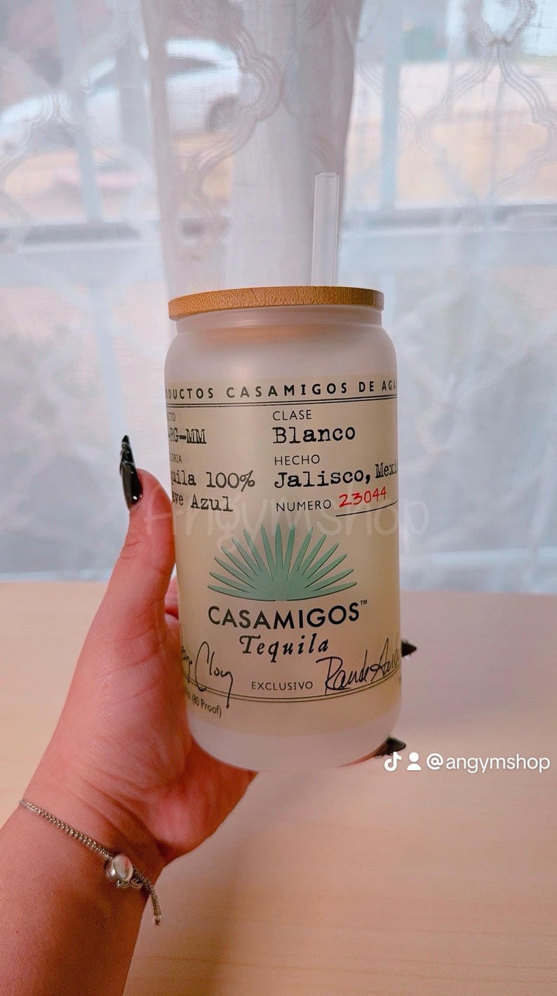 Puede incluir: Un vaso de vidrio esmerilado con tapa de bamb&uacute; y una pajita. El vaso tiene una etiqueta de tequila Casamigos con el texto "Clase Blanco", "Hecho Jalisco, M&eacute;xico", y "Numero 23044". La etiqueta tambi&eacute;n presenta un gr&aacute;fico de planta de agave verde y el logotipo de Casamigos.