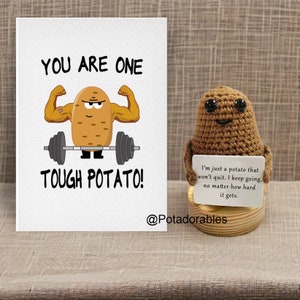 Op de afbeelding: Een kaart met een cartoon-aardappel die gewichten heft. De kaart zegt "You are one tough potato!" en heeft de tekst "@Potadorables" onderaan. Een gehaakt aardappel speelgoed houdt een bord vast met de tekst "I'm just a potato that won't quit. I keep going, no matter how hard it gets."