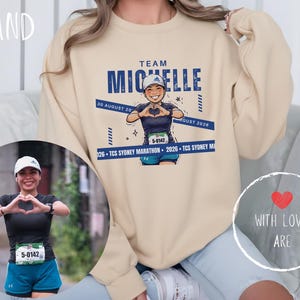 Puede incluir: Sudadera color arena con un gráfico de un corredor y el texto "Team Michelle". El diseño incluye la fecha "30 de agosto de 2026" y "TCS Sydney Marathon". Una foto de un corredor está en un marco circular. Las palabras "With Love, Are" están en un corazón.