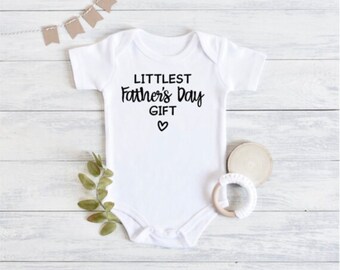 May include: White baby grow with black text that reads "Littlest Father's Day Gift" with a small heart symbol.