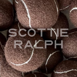 May include: A collection of dark brown tennis balls with a fuzzy texture and white seams. The text SCOTTIE RALPH is overlaid in a semi-transparent white font across the centre of the image, partially obscuring the brown tennis balls.