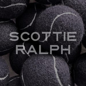 May include: A collection of dark grey tennis balls with a fuzzy texture and white curved seams. The text SCOTTIE RALPH is overlaid in a light grey sans-serif font across the centre of the image, partially obscuring the tennis balls.