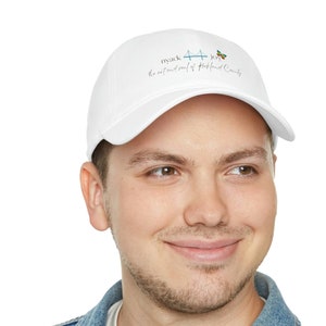 May include: White baseball cap with a blue and green butterfly graphic and the text "my suck + joy the natural soul of Rockland County".