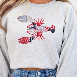 Sudadera con langosta bordada: cuello redondo náutico con patchwork