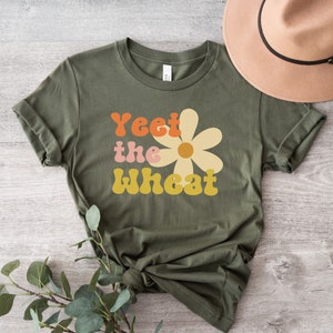 May include: A green t-shirt with a daisy graphic and the text "Yeet the Wheat" in a retro font.