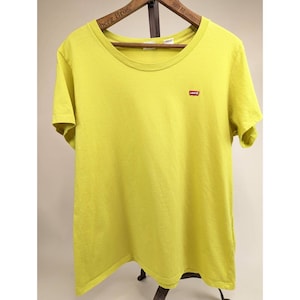 May include: A chartreuse-colored t-shirt with a crew neck and short sleeves. A small red Levi's logo is on the left chest. The shirt is displayed on a wooden hanger.