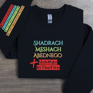 Puede incluir: Sudadera negra con un estampado gráfico colorido que dice "Shadrach Meshach Abednego 4th Man In The Fire".