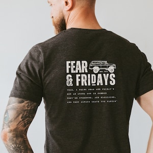 May include: A dark gray t-shirt with a white graphic print of a vintage off-road vehicle and the text "FEAR & FRIDAYS" with a quote about fear and Fridays.