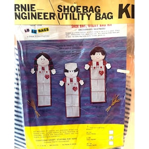 May include: A Lo Lo Bags craft kit for a shoe bag and utility bag featuring three doll-like figures in striped overalls with red accents. The packaging includes the text Bernie Engineer Utility Bag and instructions for a stitch and sew project.