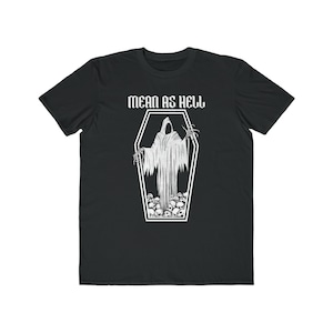 May include: Black t-shirt with a white graphic of a grim reaper inside a coffin, surrounded by skulls. The text "MEAN AS HELL" is above the coffin. The shirt is made of a soft, comfortable material.