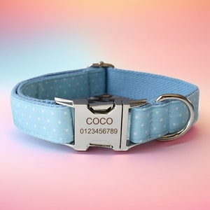 May include: A light blue dog collar with white polka dots and a silver buckle. The buckle is engraved with the name "Coco" and the phone number "0123456789".
