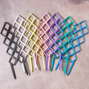 May include: A set of ten colourful plastic grid panels, each with a different colour, including black, white, yellow, pink, purple, blue, and green. The panels are arranged in a fan shape and have a diamond pattern.