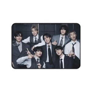 May include: A rectangular desk mat featuring a high-resolution group photograph of seven individuals dressed in formal attire, including grey vests, white button-down shirts, and dark ties, posed against a dark, grid-patterned background.