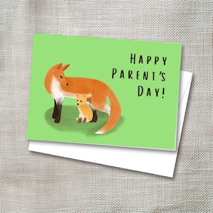 May include: A greeting card with a green background features a watercolor illustration of a fox and a smaller fox cub. The text "HAPPY PARENT'S DAY!" is written in black. The card is inside a white envelope.