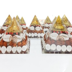 May include: Set of six clear crystal pyramids filled with various natural elements, including white seashells, red and brown beads, and a gold-colored miniature pagoda on top.