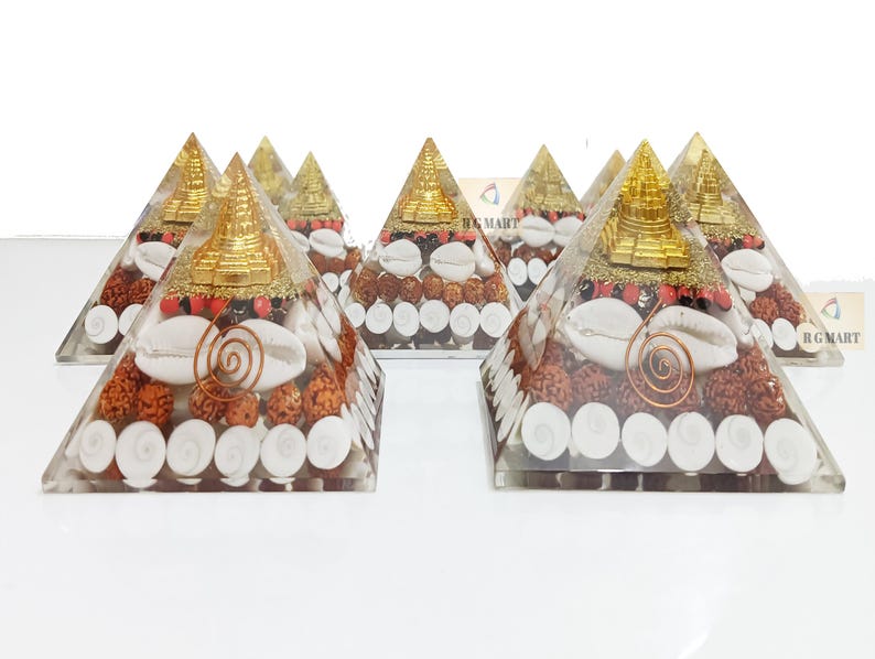 May include: Set of six clear crystal pyramids filled with various natural elements, including white seashells, red and brown beads, and a gold-colored miniature pagoda on top.