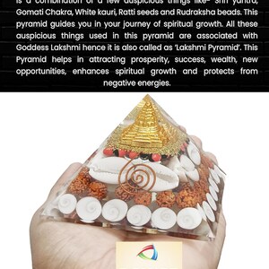 May include: A clear glass pyramid filled with various items, including white seashells, red and brown beads, and a gold-colored Shri Yantra. The pyramid is being held in a hand. The text "RG MART" is visible in the lower right corner of the image.