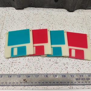 May include: Four blank floppy disks, two are red and two are blue. The disks are arranged in a row, with the red disks on either end and the blue disks in the middle.