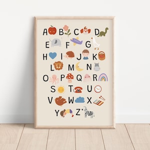 Op de afbeelding: Een ingelijste alfabetposter met kleurrijke illustraties van objecten en dieren voor elke letter. De poster heeft een lichtbeige achtergrond en een houten lijst. De illustraties omvatten een appel, een bloem, een clown, een dinosaurus, een olifant, een vliegtuig, een gans, een hart, een egel, een jongen, een mand, een leeuw, een maan, een nijlpaard, een octopus, een paddenstoel, een spook, een regenboog, een zon, een telefoon, een klok, een vogel, een wolk, een xylofoon en een zebra.