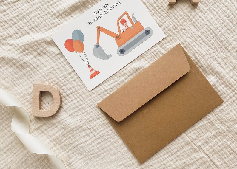 May include: A brown envelope with a white card on top. The card has a cartoon illustration of a construction worker driving a yellow excavator with a grey bucket. The card also has three balloons and a traffic cone. The text on the card reads "Einladung zu meinem Geburtstag".