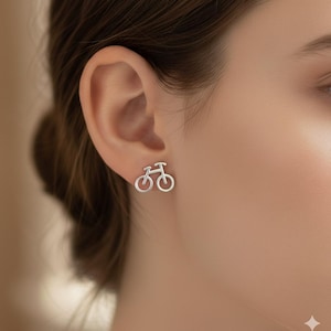 May include: Silver bicycle stud earrings. The earrings are shaped like a bicycle and are worn on the ear. The earrings are a simple, minimalist design.