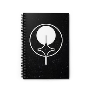 May include: Spiral-bound notebook with a black cover featuring a white geometric design. The design includes a circle, a sphere, and a stylized shape. The notebook's pages are visible along the spine.