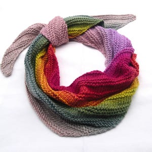 Può includere: Una sciarpa di maglia colorata con un gradiente di rosa, viola, rosso, arancione, giallo, verde e grigio.