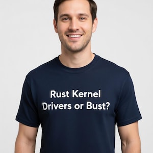 May include: A navy blue t-shirt with the text "Rust Kernel Drivers or Bust?" in white. The shirt is a crew neck style and is being worn by a person.