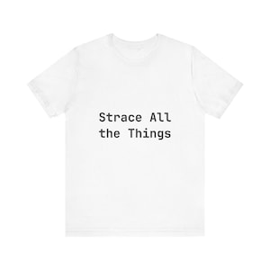 May include: White t-shirt featuring the black text "Strace All the Things". The top has a crew neck and short sleeves.