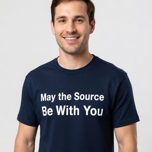 Könnte beinhalten: Ein marineblaues T-Shirt mit dem weißen Text "May the Source Be With You". Das T-Shirt hat einen Rundhalsausschnitt und wird von einer Person getragen.
