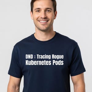 Puede incluir: Camiseta azul marino con el texto blanco "DND : Tracing Rogue Kubernetes Pods". La camiseta es de cuello redondo y la lleva puesta una persona.