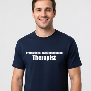 May include: A navy blue short-sleeved t-shirt featuring the white text Professional YAML Indentation Therapist printed across the chest. The garment has a classic crew neckline and a standard fit, providing a clean and simple look for everyday wear.