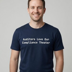 May include: A navy blue short-sleeved t-shirt featuring the white text "Auditors Love Our Compliance Theater" printed across the chest. The shirt has a classic crew neckline and a standard fit, providing a clean and straightforward appearance.