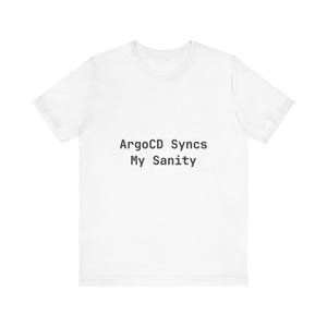 Puede incluir: Una camiseta blanca con el texto negro "ArgoCD Syncs My Sanity". La camiseta tiene cuello redondo y mangas cortas. La tela parece suave y cómoda.