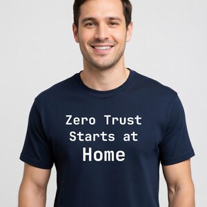 May include: A navy blue t-shirt with the white text "Zero Trust Starts at Home". The shirt is short-sleeved and appears to be made of a soft material. The person wearing the shirt is smiling.