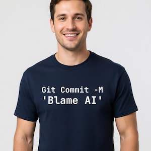 May include: A navy blue t-shirt with the text "Git Commit -M 'Blame AI'" in white. The shirt is worn by a person smiling at the camera. The t-shirt is a casual wear item.