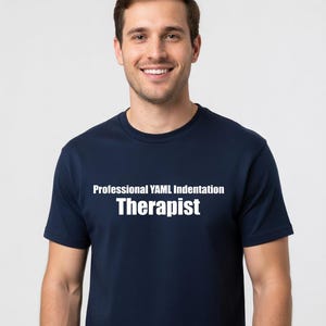 May include: A navy blue short-sleeved t-shirt featuring the white text Professional YAML Indentation Therapist printed across the chest. The garment has a classic crew neckline and a standard fit, providing a clean and simple look for everyday wear.