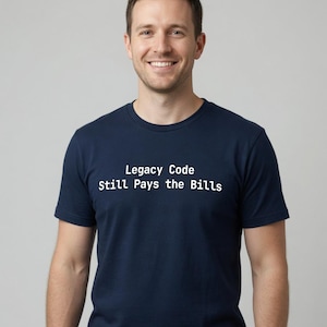 May include: A navy blue short-sleeved t-shirt featuring the white text Legacy Code Still Pays the Bills printed across the chest. The garment has a classic crew neckline and a standard fit, providing a clean and straightforward appearance.