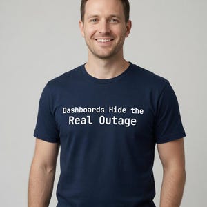 May include: A navy blue short-sleeved t-shirt featuring the white text "Dashboards Hide the Real Outage" printed across the chest. The shirt has a classic crew neckline and a standard fit, providing a clean and simple look for casual wear.